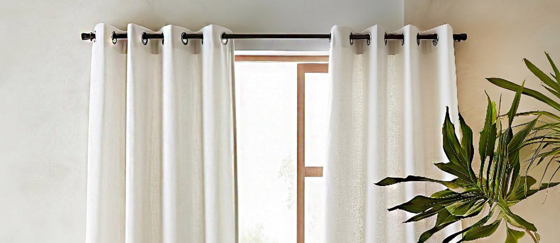 A natural linen tab top curtain hanging from a rod, softly draped with visible texture and gentle folds. The fabric has a matte finish and a relaxed, organic look